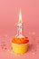 Number 1 candle in a cupcake against a pastel pink background. First bithday cake