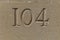 Number 104 carved in a limestone ashlar wall