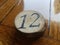The number 12 on a circular piece of wood on a waxed wooden table
