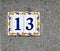 Number 13, thirteen, a decorative tile blue and yellow on a gray background, isolated.
