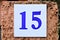 Number 15, fifteen, blue digits on a white tile.
