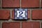 Number 2 vintage antique ceramic tile house number on brick wall with flowers
