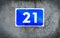 Number 21, twenty-one, blue plate with a white number, on a wall.