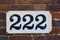 Number 222 on  brown brick wall, black numerals
