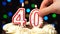Number 40 on top of cake - forty birthday candle burning - blow out at the end. Color blurred background