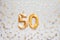 Number 50 fifty golden celebration birthday candle on Festive Background.
