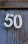A number 50 hanging in front of a rustic blue door
