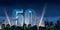 Number 50 in thick blue font lit from below with floodlights floating in the middle of a city center with tall buildings with