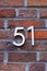 Number 51 metal house number on brick wall