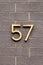Number 57 metal house number on gray brick wall