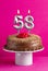 Number 58 candle - Chocolate cake on pink background