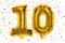 The number of the balloon made of golden foil, the number ten on a white background with multicolored sequins.