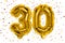 The number of the balloon made of golden foil, the number thirty on a white background with multicolored sequins.