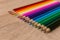 A number of colored pencils in a row on wooden background. Colorful photography. Selected focus on white