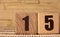 The number fifteen on a wooden cube on a beige background. Cube on a bamboo Mat