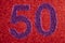 Number fifty purple over a red background. Anniversary.