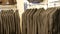 Number of identical-colored men`s suits hanging on a hanger in a clothing store in a mall