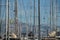 The number of masts of sailboats with the blue sky and mountains on a background, a sail regatta, reflection of masts on