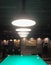 A number of pendant lamps illuminate a billiard table with green coating and billiard balls.