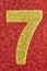 Number seven golden color over a red background. Anniversary