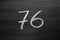 Number seventy six enumeration written with a chalk on the blackboard