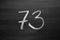 Number seventy three enumeration written with a chalk on the blackboard