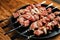 A number of skewers with meat laid out in a black plate. Close-up of mouth-watering pieces of beef ready to fry