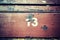 Number thirteen painted on an old wooden seat.