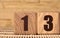 The number thirteen on a wooden cube on a beige background. Cube on a bamboo Mat