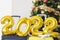 Numbers 2022 on suitcases against the background of Christmas tree