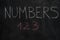 Numbers word and first three letters on black chalkboard