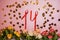 Numeral 14 made of red confetti ribbon and flowers on a pink background. Valentine`s Day