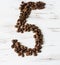 Numeral from the grains of coffee on a light wooden background. Selective focus.