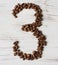 Numeral from the grains of coffee on a light wooden background. Selective focus.