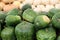 Numerous pumpkins and squash in green, white, yellow and tan colors on table at market