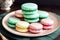 Numerous vibrantly hued macarons are elegantly arranged on a plate resting atop a table.