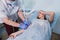 Nurse attaching intravenous tube to patient`s hand in hospital bed