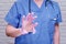 A nurse in a blue uniform shows a torn protective glove. Doctor in a torn medical glove, close-up