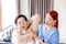 Nurse caregiver wearing scrubs exercises with a senior Asian woman to relieve a frozen shoulder of the senior patient.