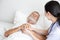 Nurse cares for elderly man sleeping in bed