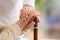 Nurse comforting elderly woman with cane against blurred background. Assisting senior generation