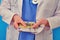 Nurse counts in her hands the money in European currency, closeup. Doctor in medical clothes with euro cash, blue background