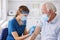 Nurse disinfecting senior patient vaccine application spot