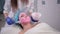 Nurse doctor makes woman facial massage, causes pink mask with brush