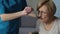 Nurse feeding disabled woman at home wiping with napkin, helplessness in old age