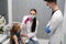 A nurse is getting ready to inject a little girl with a previously prepared vaccine. The young apprentice tries to talk