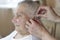 A nurse helps a 90 year old grandmother insert a hearing aid into her ear