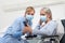 Nurse helps with cell phone to contact the elderly lady`s family in the wheelchair, wearing surgical protective medical masks in