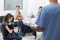 Nurse Holding Form While Owners With Pets Waiting In Clinic