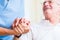 Nurse holding hand of senior man in rest home